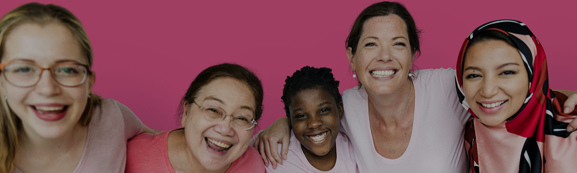 Group of women smiling at the camera on pink background