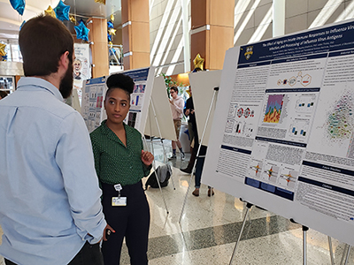 Raven Osborn, third-year TBS-IIMP trainee, explains her research to a peer at the Annual TBS Symposium.