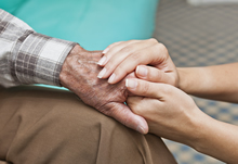 Woman holding hand of elderly man