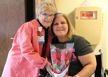 Rose poses for a picture with a patient while making annual holiday poinsettia deliveries.