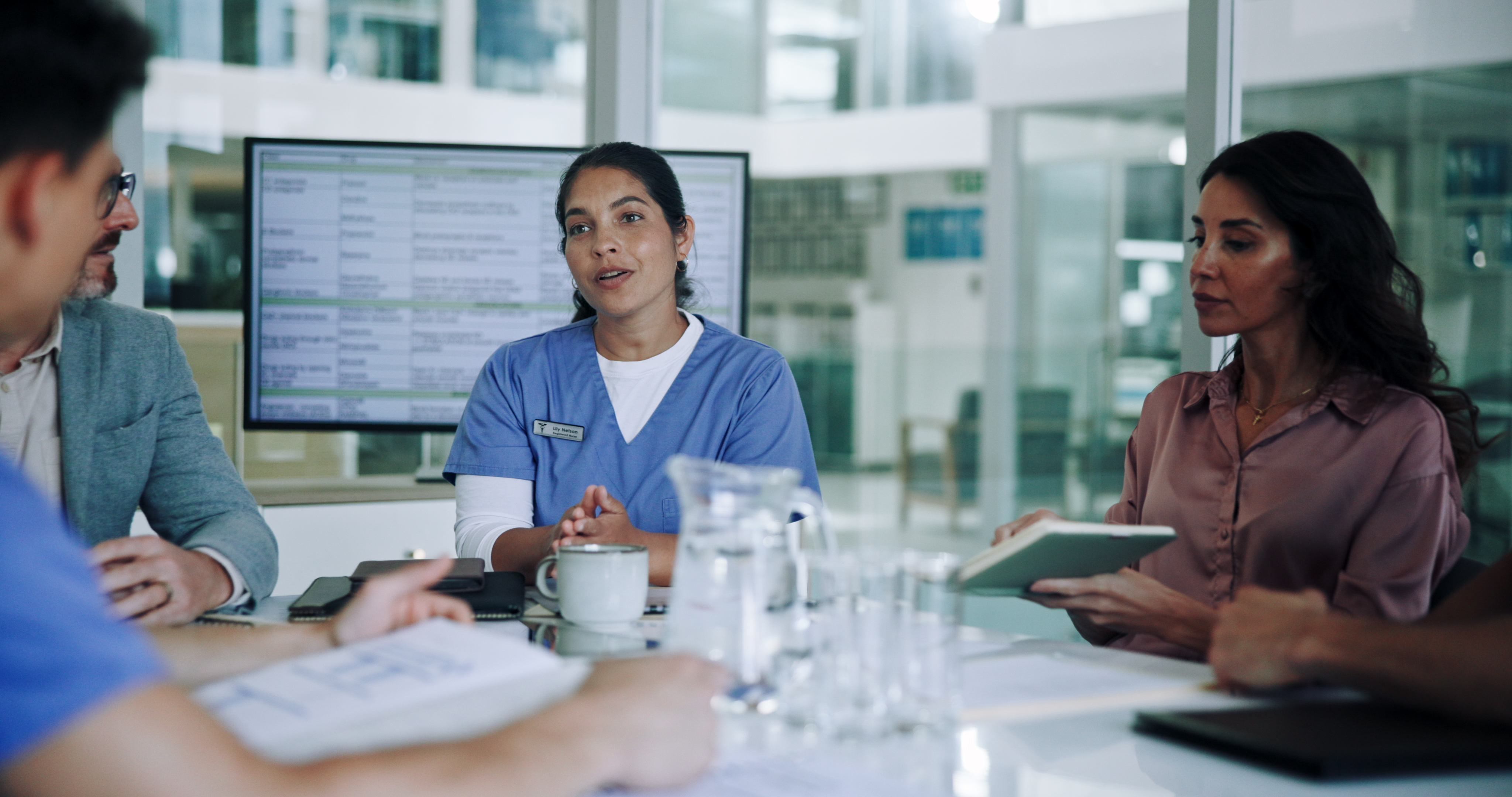 Nurse talking to colleagues with computer screen in background