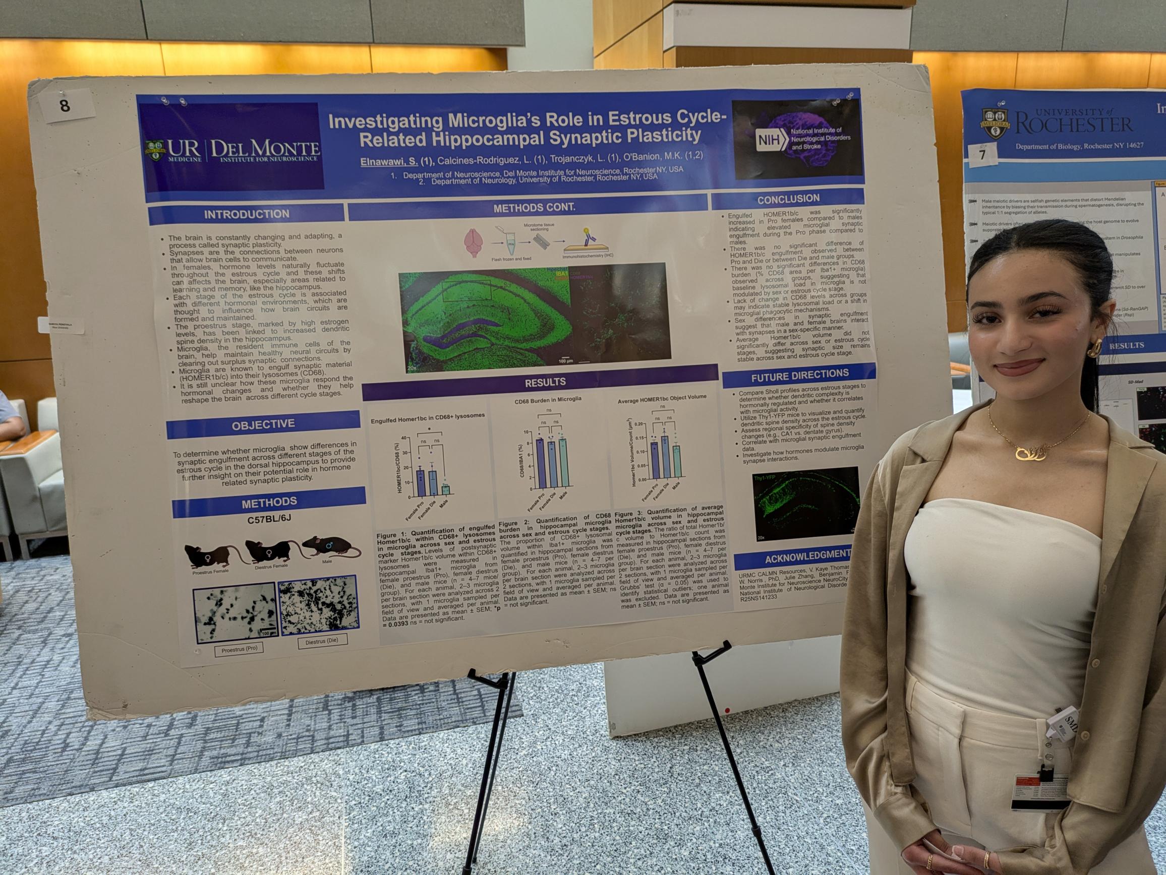 student stands next to scientific poster