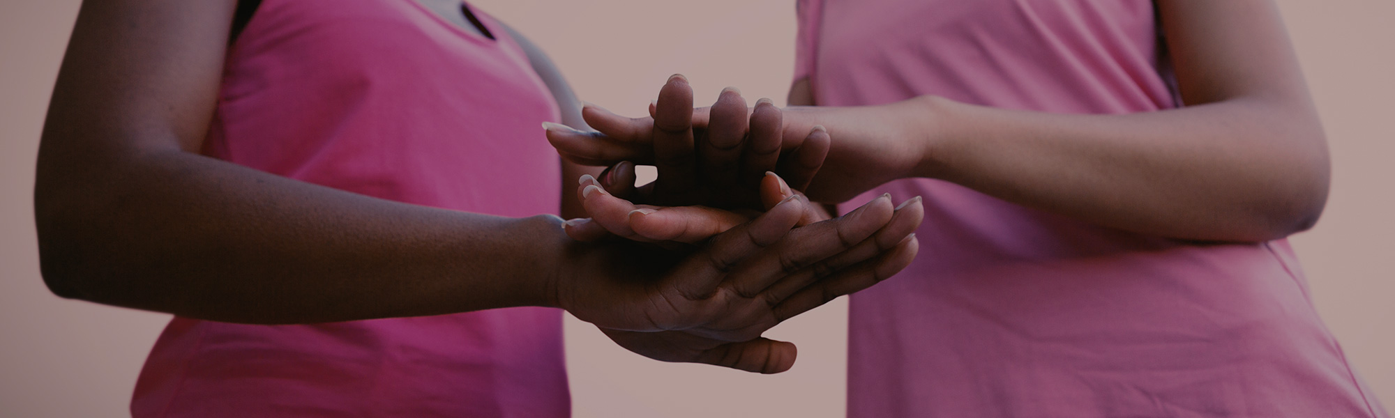 Two women in pink piling hands on top of each other