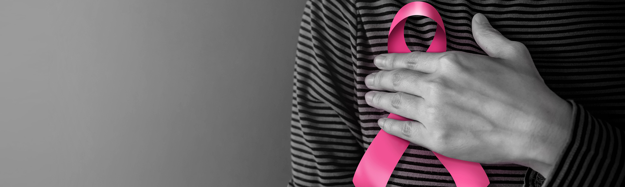 Woman holding a breast cancer awareness ribbon to her chest