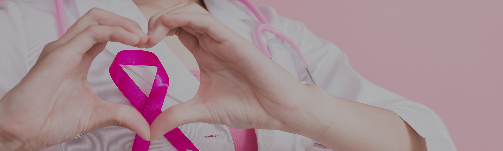 Doctor holding hands in a heart shape around a pink breast cancer awareness ribbon