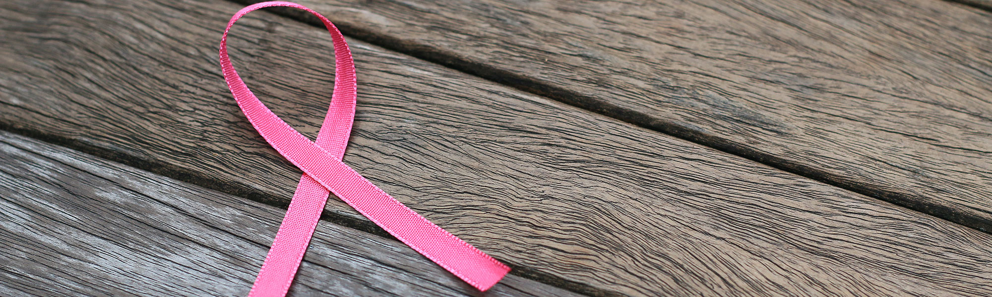 Breast cancer awareness ribbon laying on wood grain