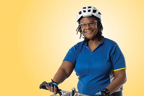 woman wearing helmet with blue shirt holding a bike