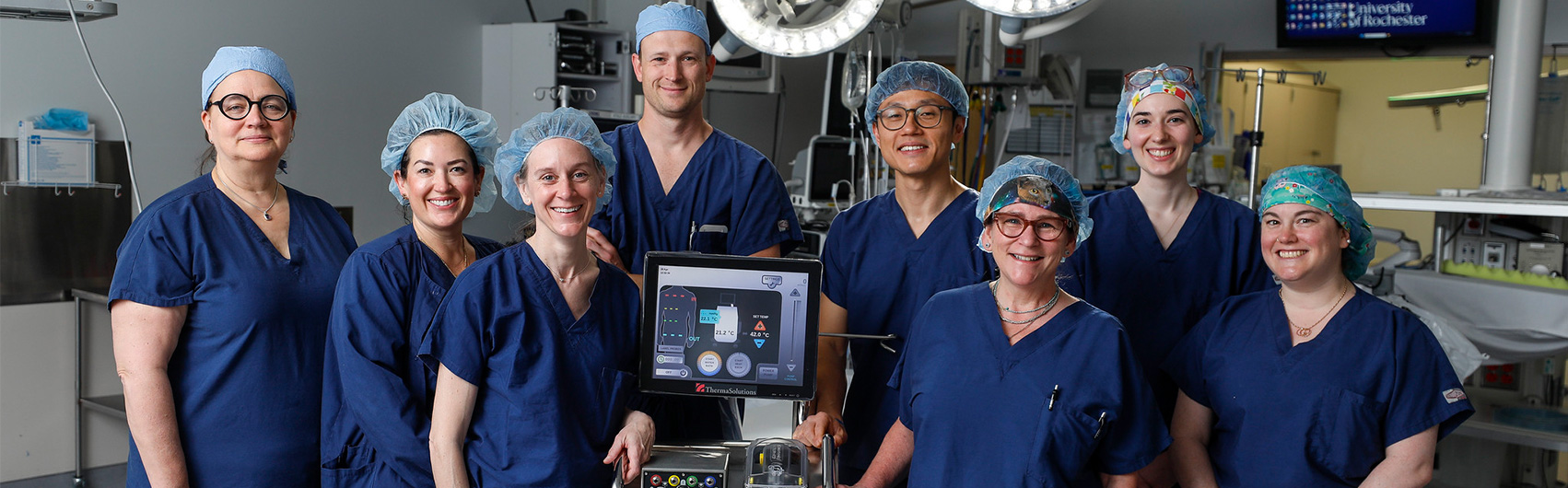 A group of people in blue scrubs in a medical setting.