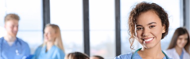 Health professional smiling at the camera with coworkers in the background