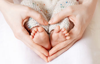 Heart hands around baby feet