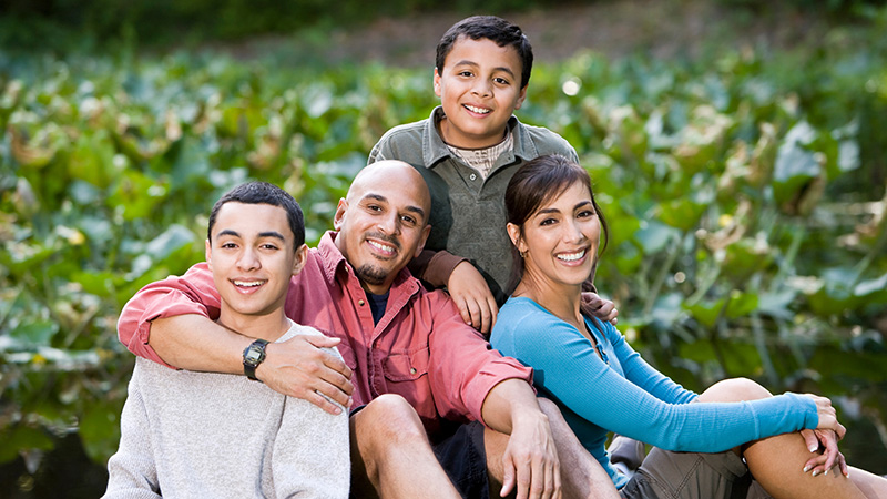 Smiling family of four outside, parents and two children