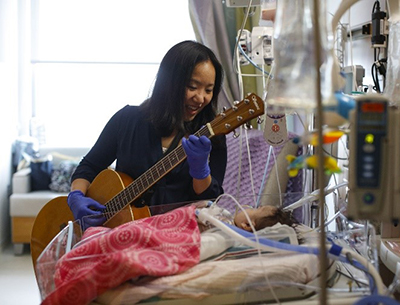 Music Therapist playing the guitar for a baby.