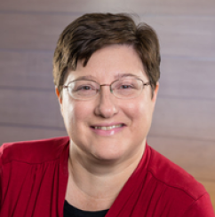 person wearing glasses smiling at camera, wearing red