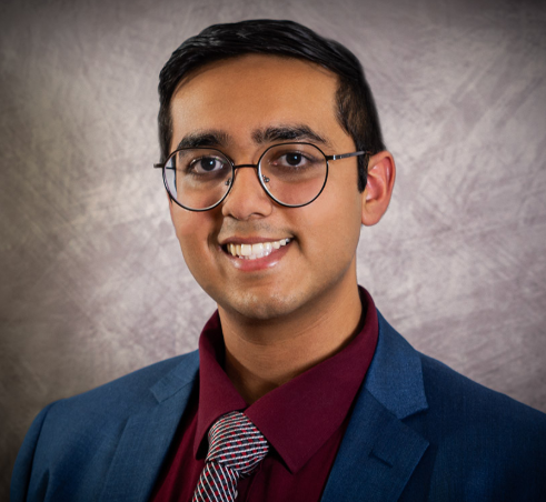 Person wearing glasses and suit smiling at camera