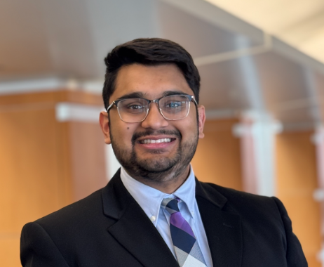 Person with glasses wearing suit and smiling at the camera