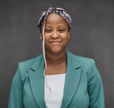 Person with braided hair wearing white shirt and turquoise blazer smiling at camera