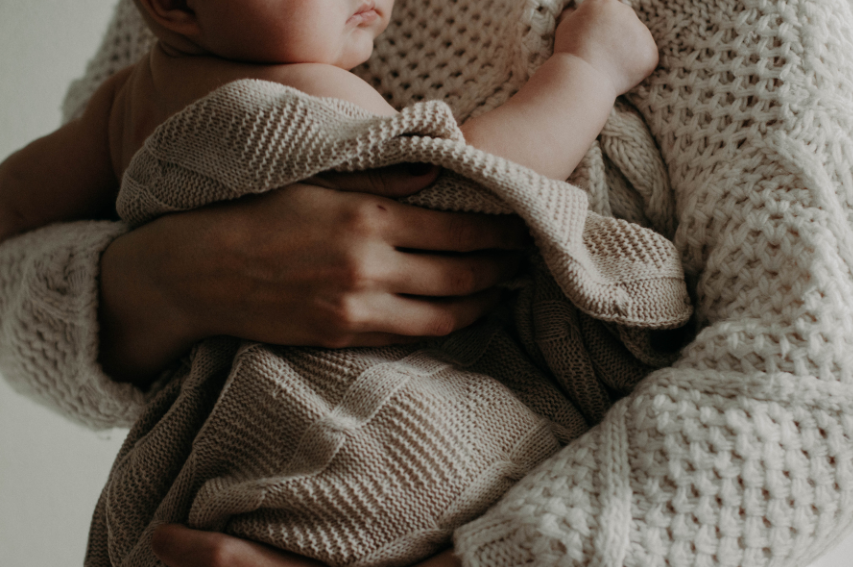 person holding infant wrapped in blanket