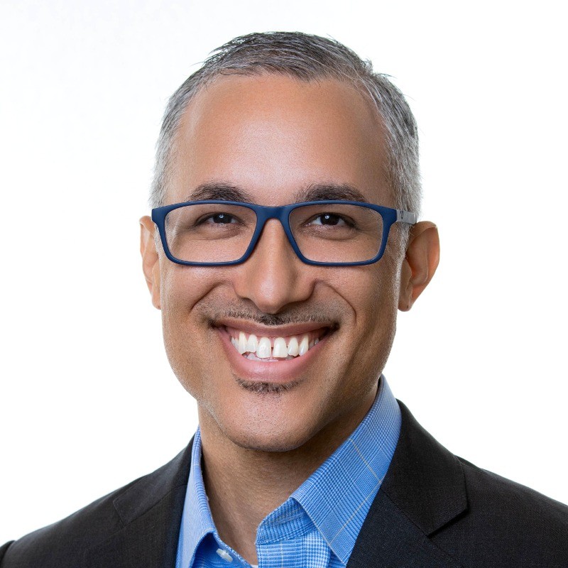 Person wearing glasses and business attire, smiling at camera