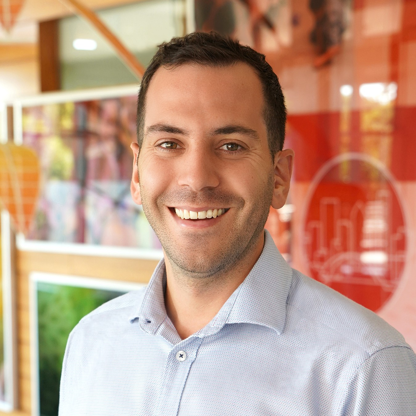 Person standing in front of colorful building walls smiling at camera