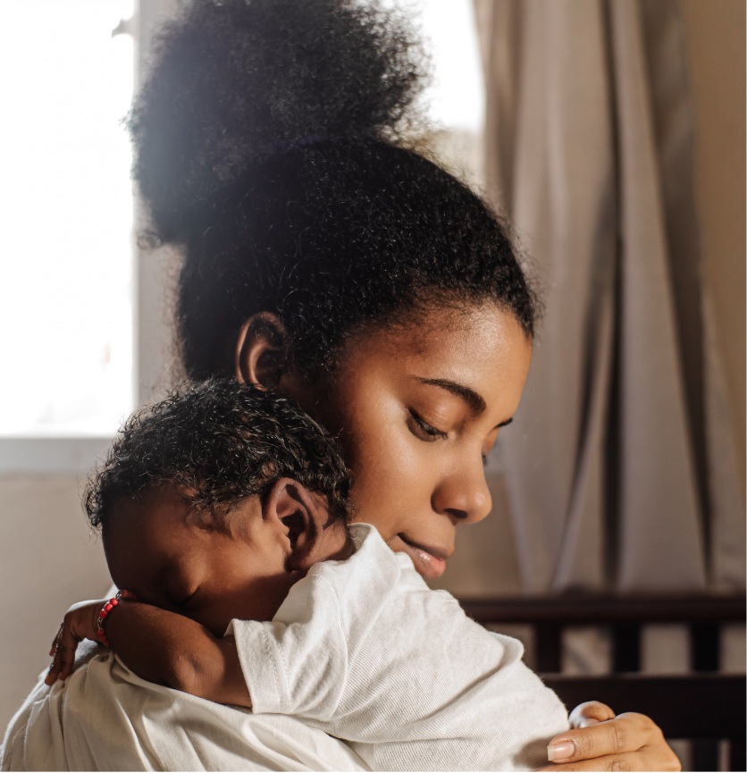 mother holding infant against shoulder