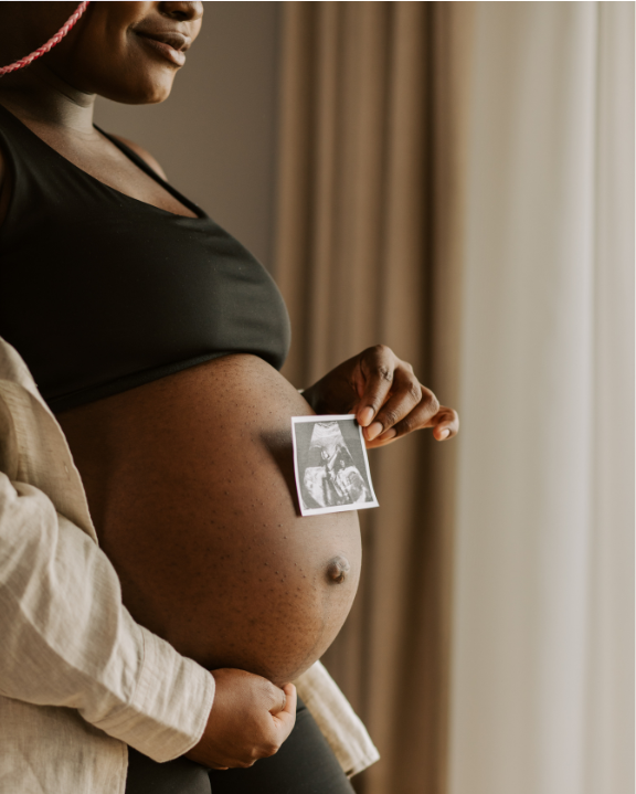 Pregnant woman standing showing baby bump with ultrasound
