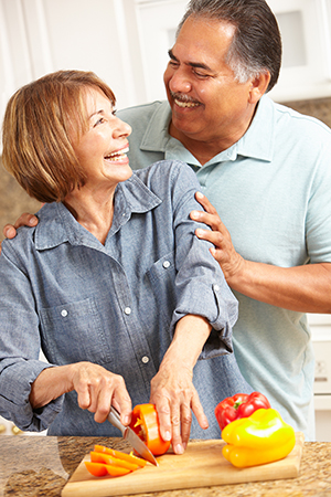 Man and Woman Laughing Together While Woman Cuts Peppers