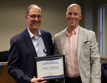 Holloway and Auerbach pose with a certificate awarded to Auerbach