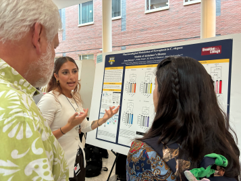 student stands next to scientific poster