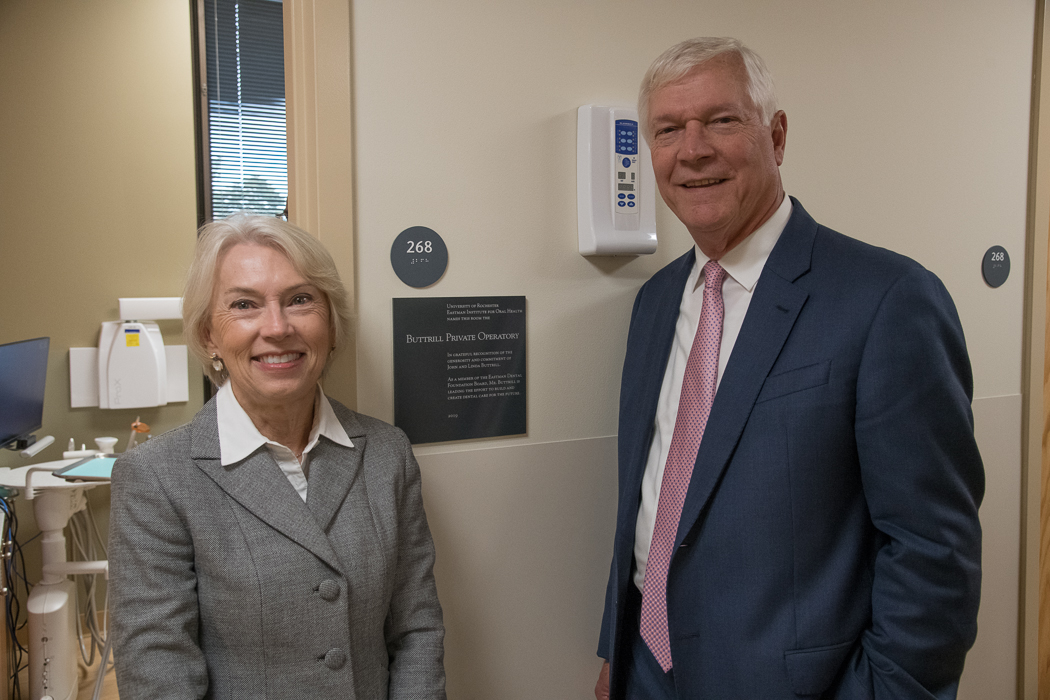 a man and a woman in suits stand next to a plaque reading "Buttrill Private Operatory"