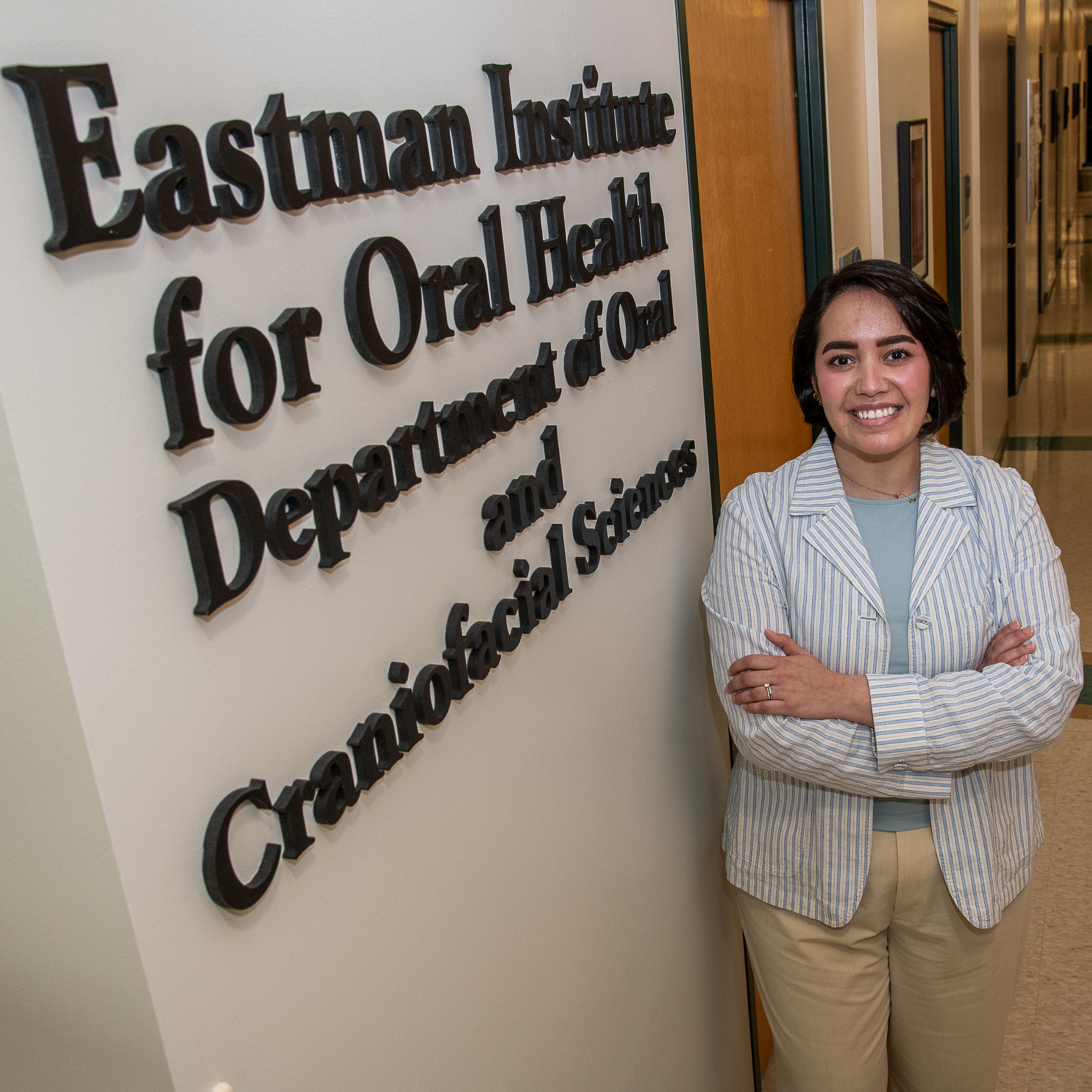 Dr. Nora Alomeir poses next to the sign for the EIOH Department of Oral and Craniofacial Sciences.