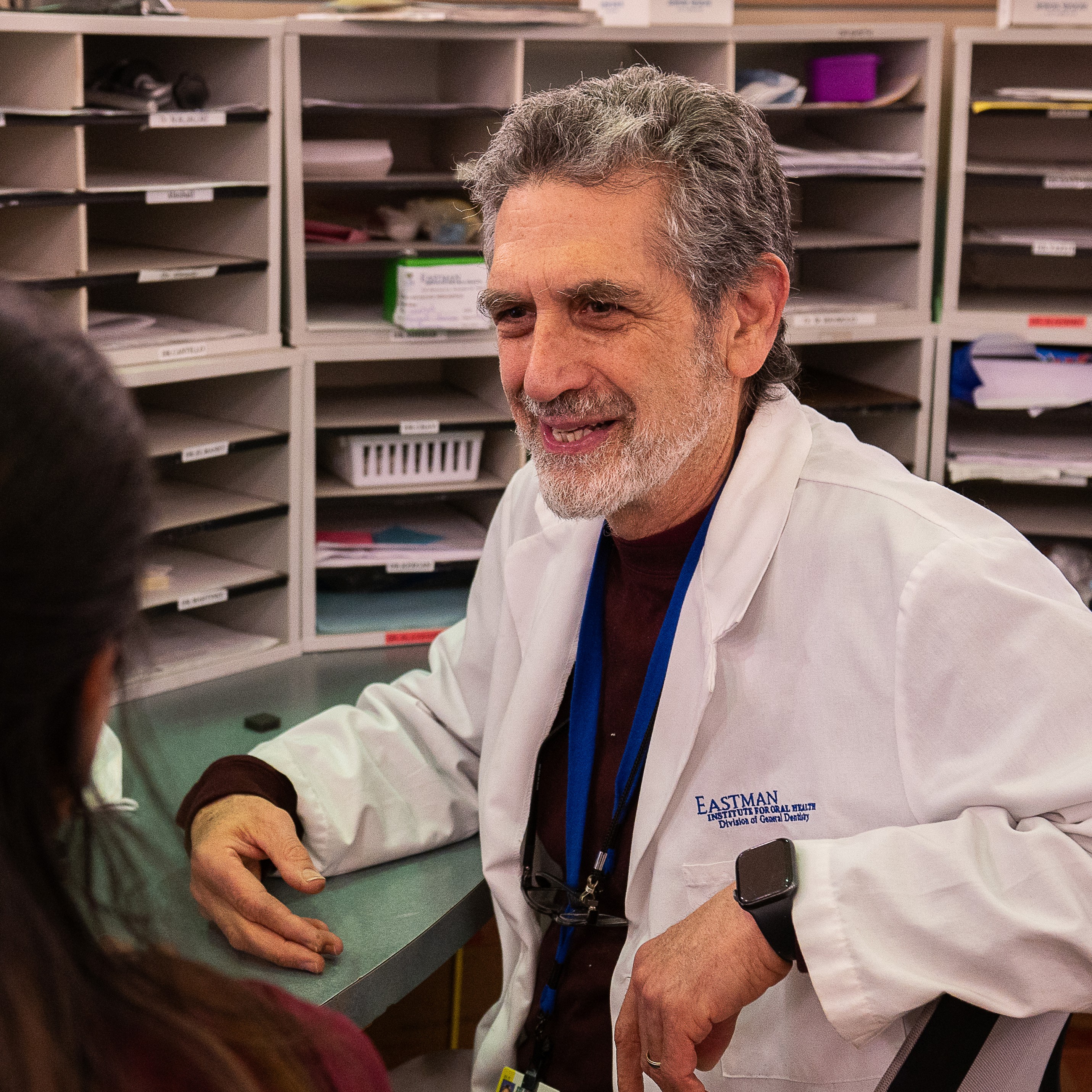 Dr. Ira Kamp sits at a desk talking to a resident.