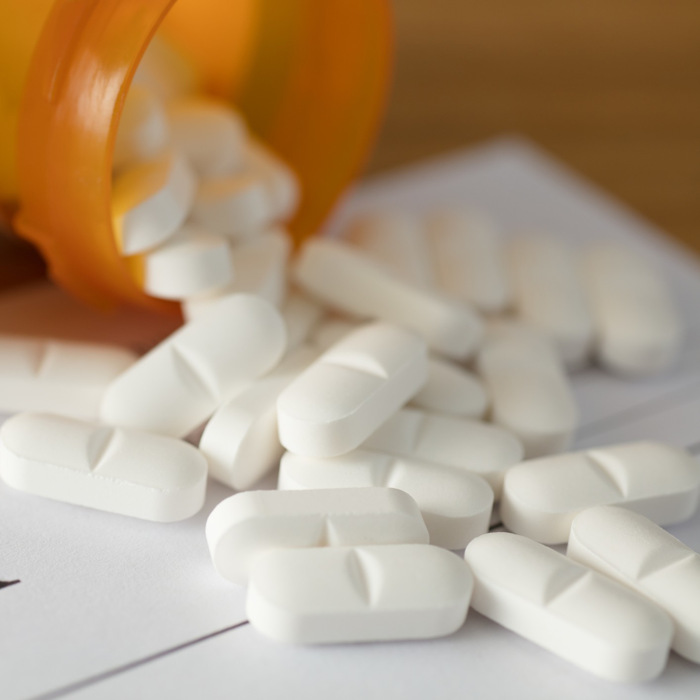 Prescription pills falling out of a bottle.