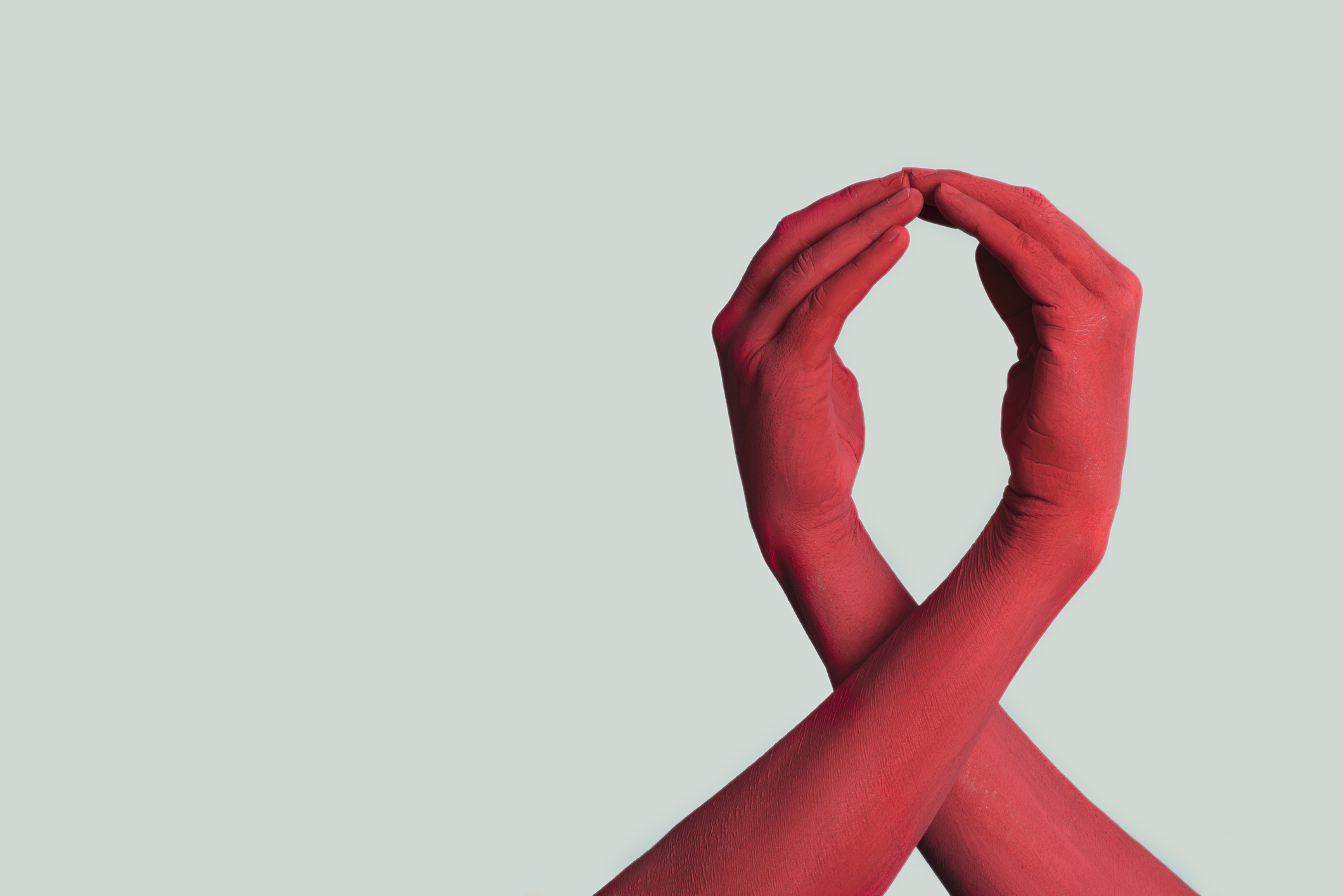 The shape of a red ribbon, formed by 2 hands and arms painted red.