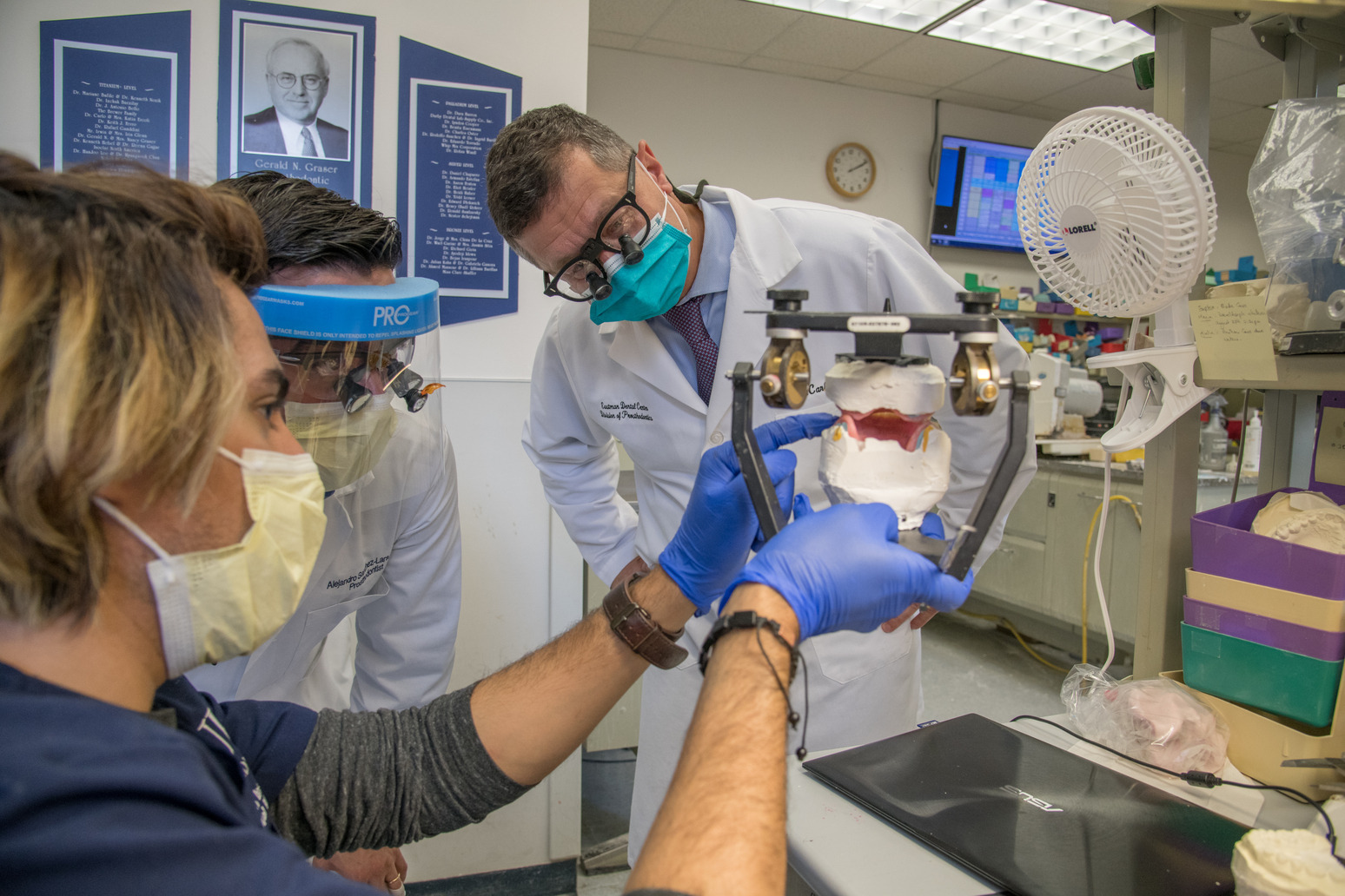 dentists in lab coats work on a dental prosthetic in the lab.