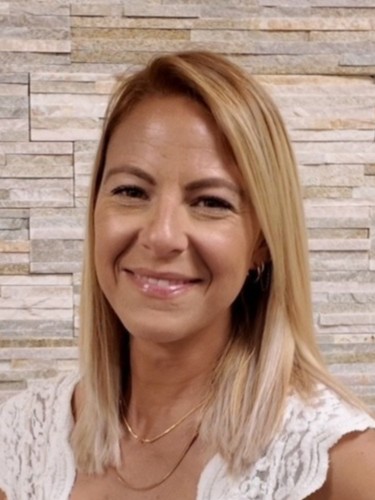A portrait of Meg Taylor, a woman with tanned skin and shoulder-length bleached hair.