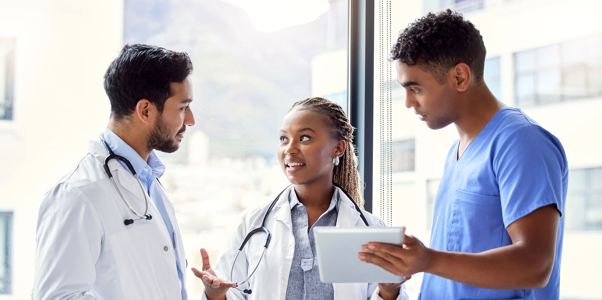 Two male providers in discussion with a female provider in a hallway