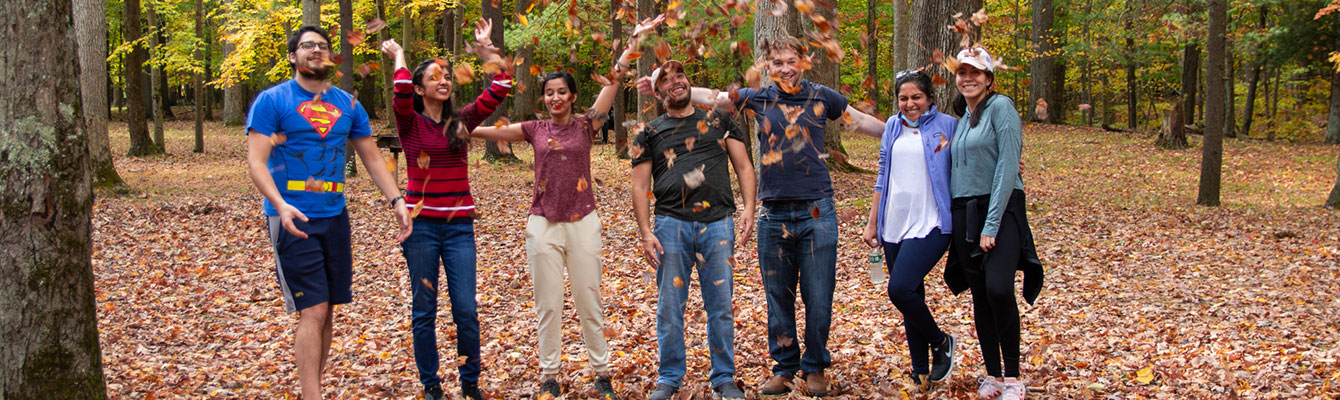 banner image of residents in woods throwing leaves