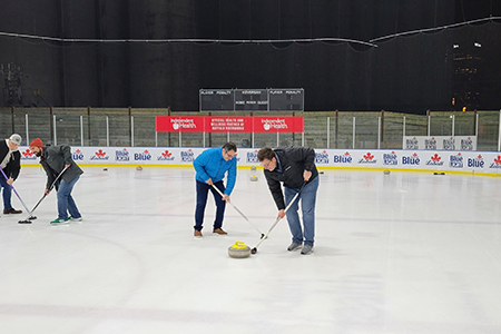 Fellows Sweeping the Ice at Curling