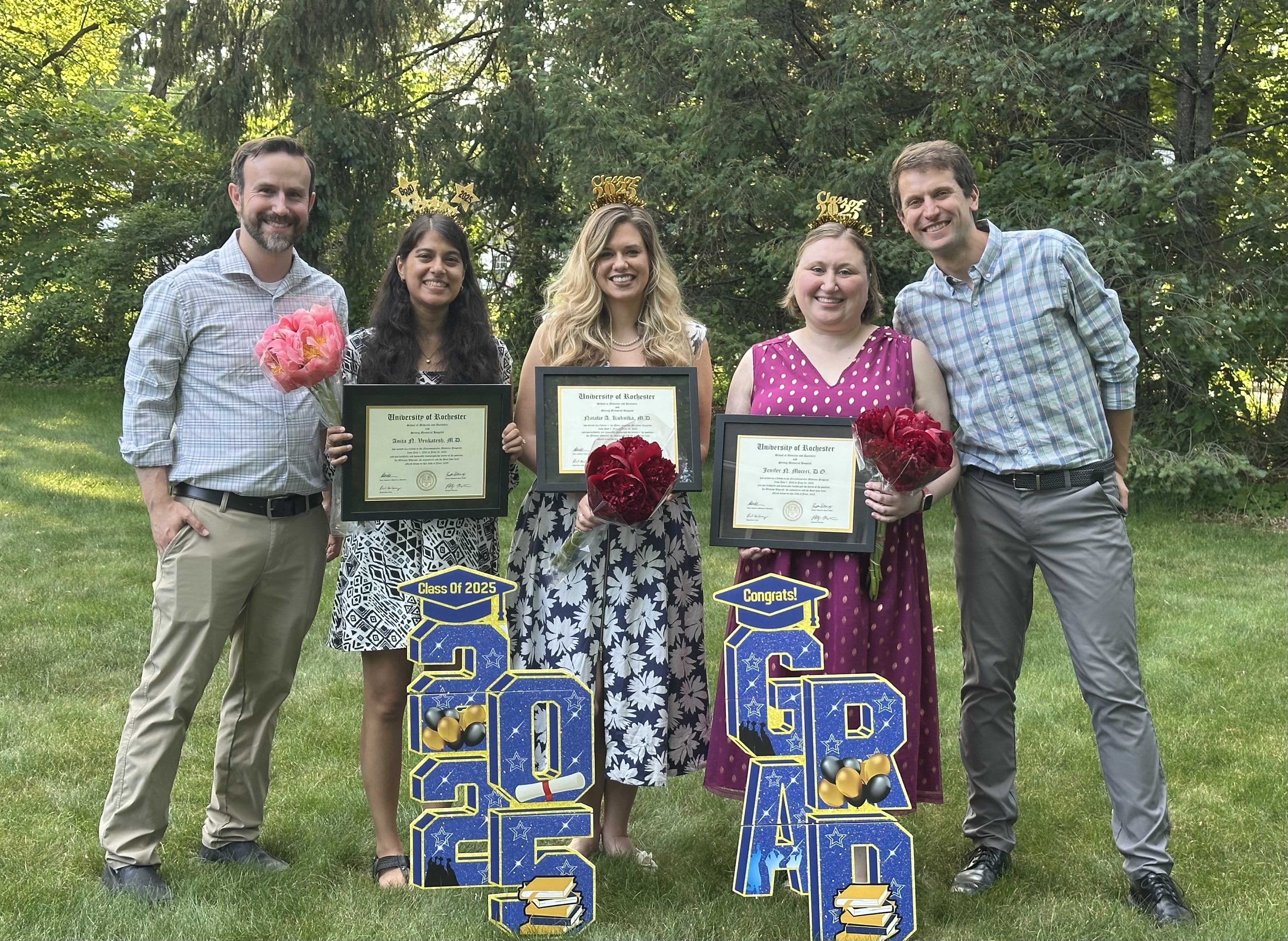 Graduates posing with certificates and celebratory decorations.