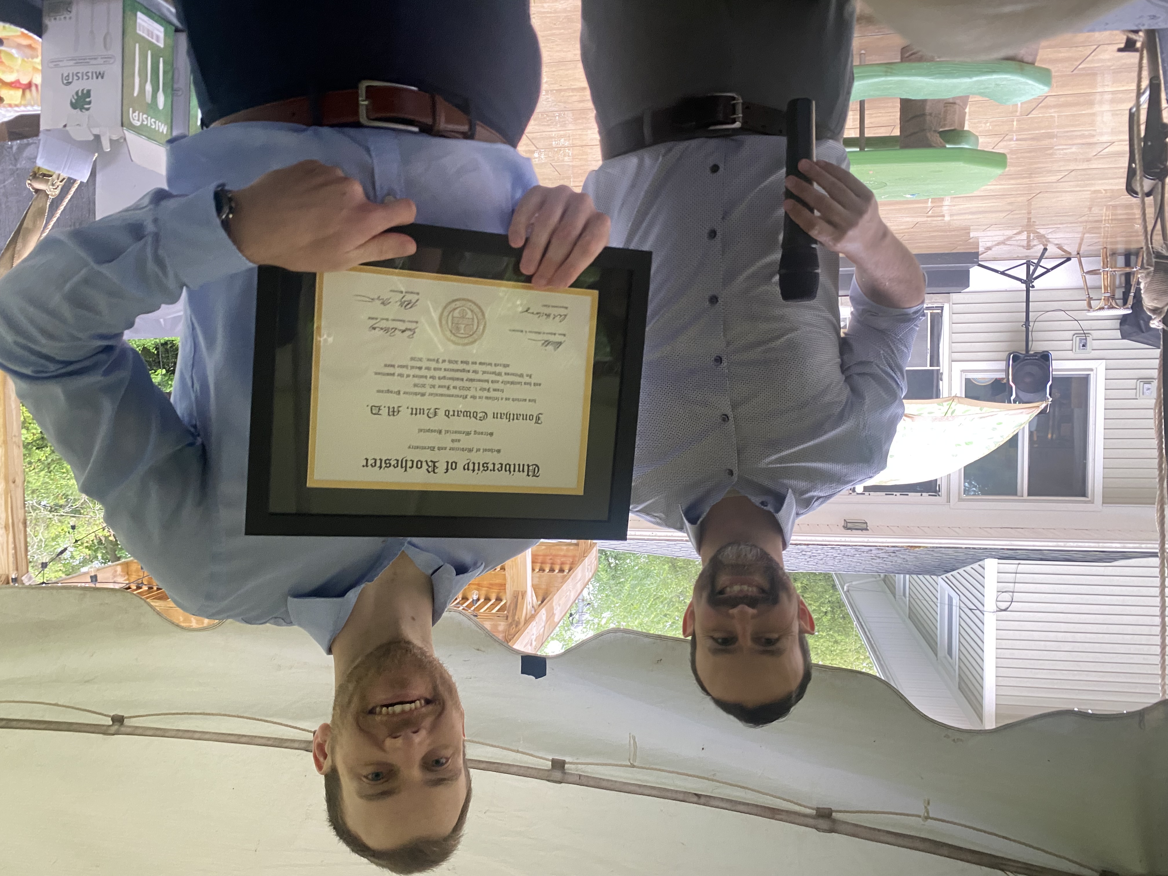 A graduating fellow holding a certificate with a faculty member.