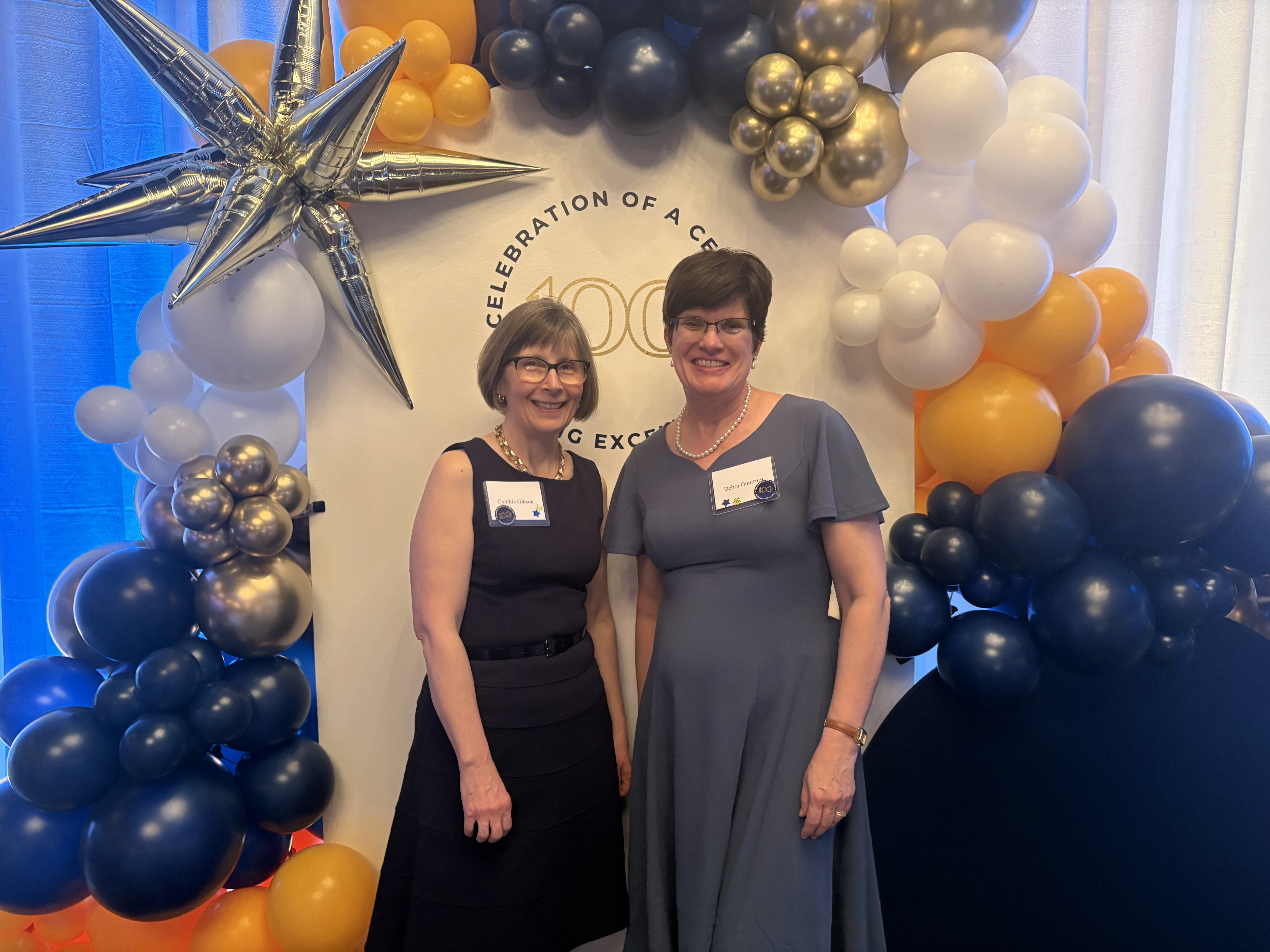 Two colleagues posing in front of the Winter Ball balloon display.