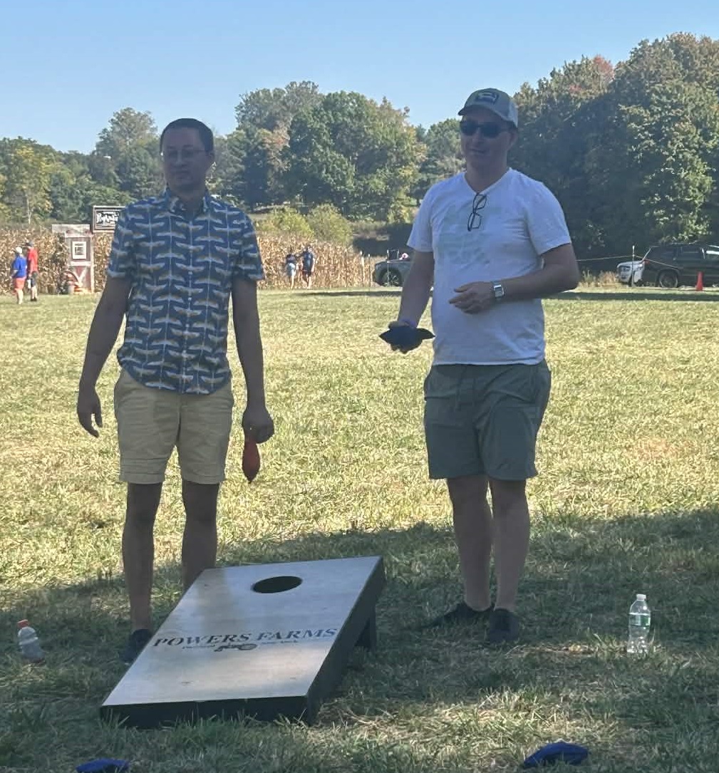 Two team members playing cornhole outdoors.