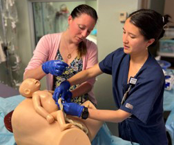 PGY-1 Residents practicing delivering a baby with a dummy
