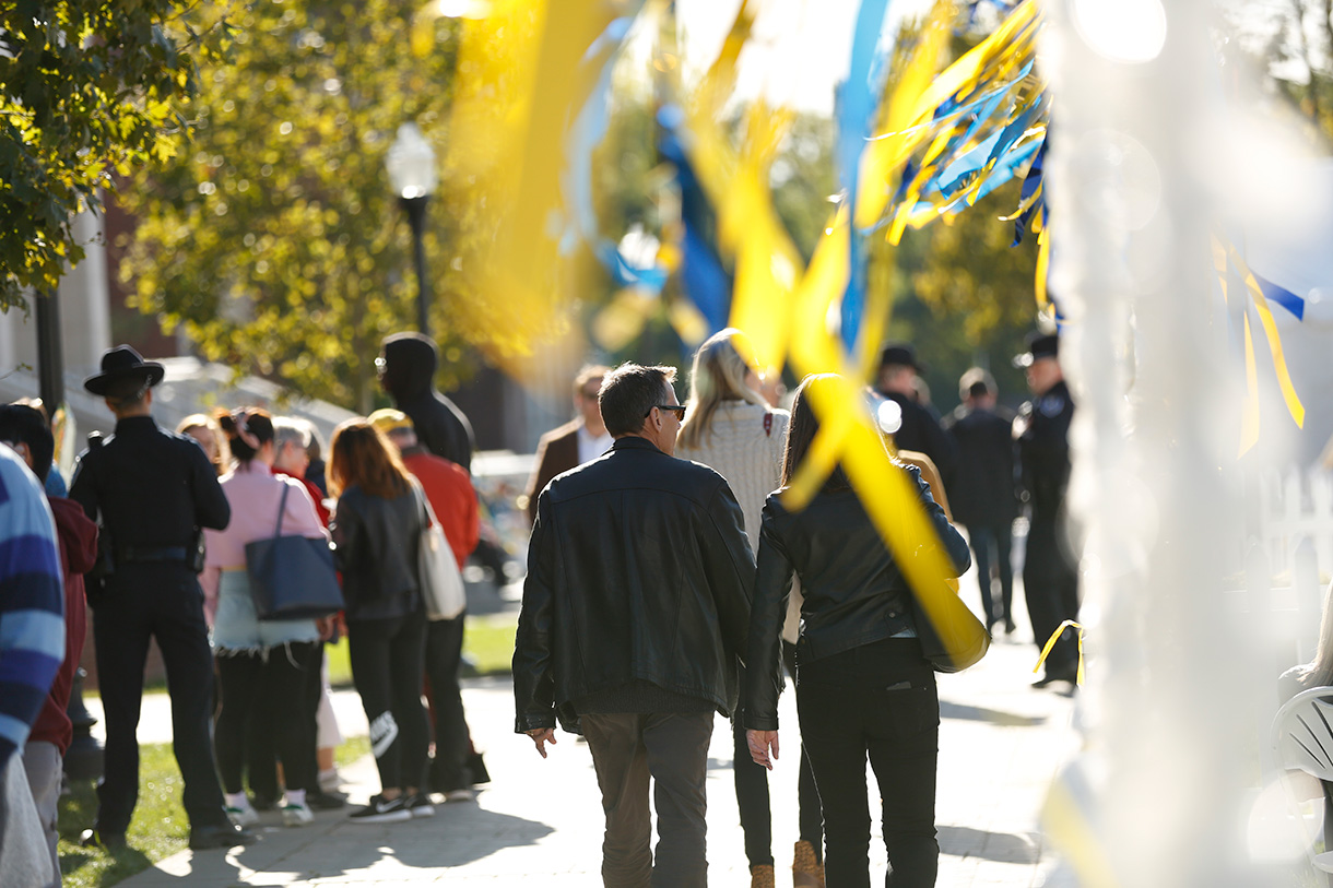 people walking outside during Meliora Weekend past blue and yellow streamers