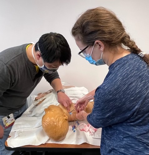 Photo of residents practicing skills on a dummy.