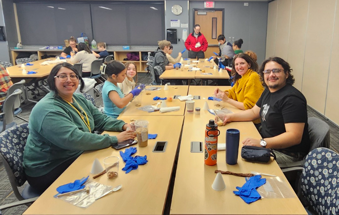 Toxicology trainees sitting around a table assisting youths in activities