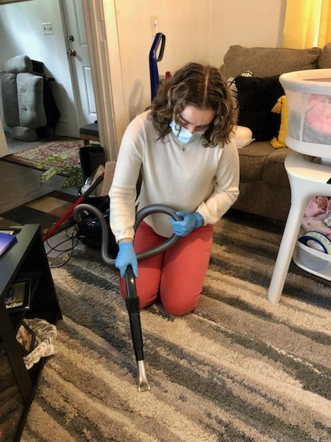 Women kneeling on carpet collecting a dust sample.