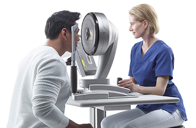 Provider in a blue shirt using InnovEyes system on a male patient