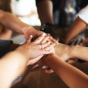 Hands stacked together to represent community support and partnership.