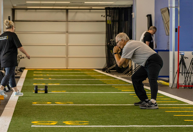 A man lunging and stretching in an open gym